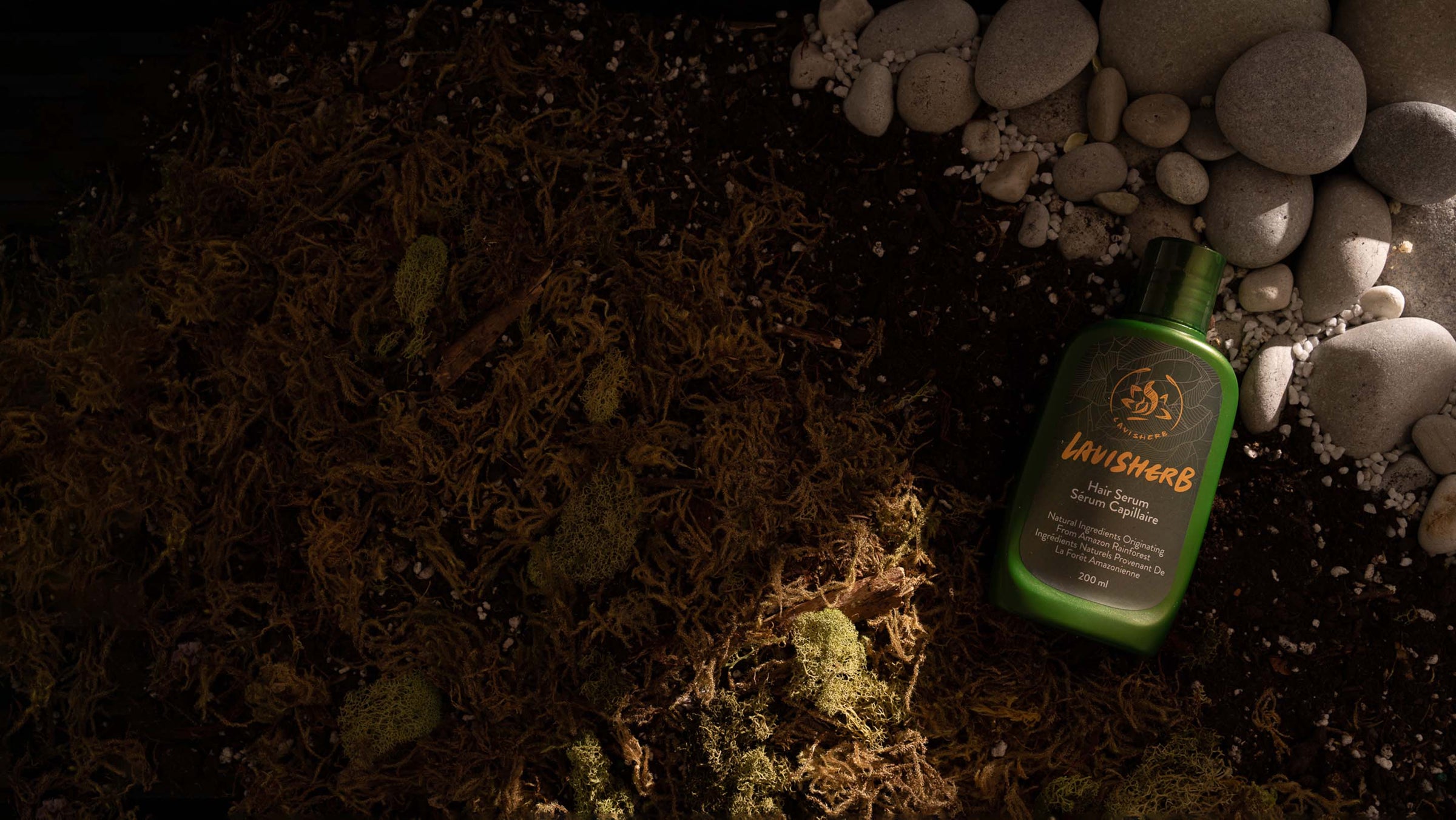 Lavisherb hair serum bottle in a natural rainforest environment with river rock and moss
